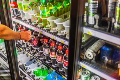 Customer selecting a drink from a convenience store cooler